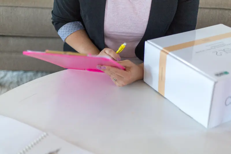 Hands filling in a form on a clipboard